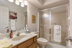 A well-organized bathroom featuring a sink, toilet, and shower with a glass door.