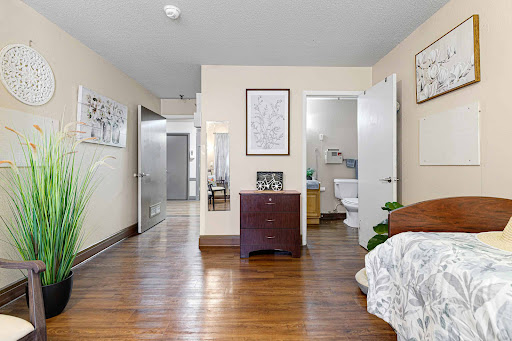 A cozy bedroom featuring wooden flooring, decorative wall art, and an adjacent bathroom.