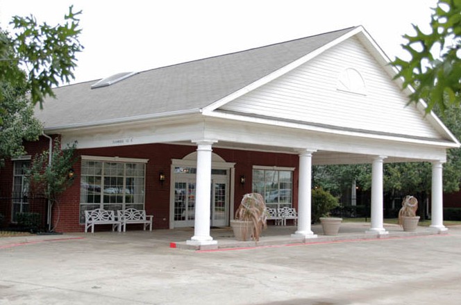 A brick building with a covered entrance supported by columns.