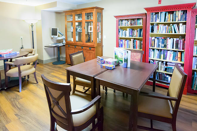 A cozy library space with bookshelves, a wooden table, and chairs for reading.