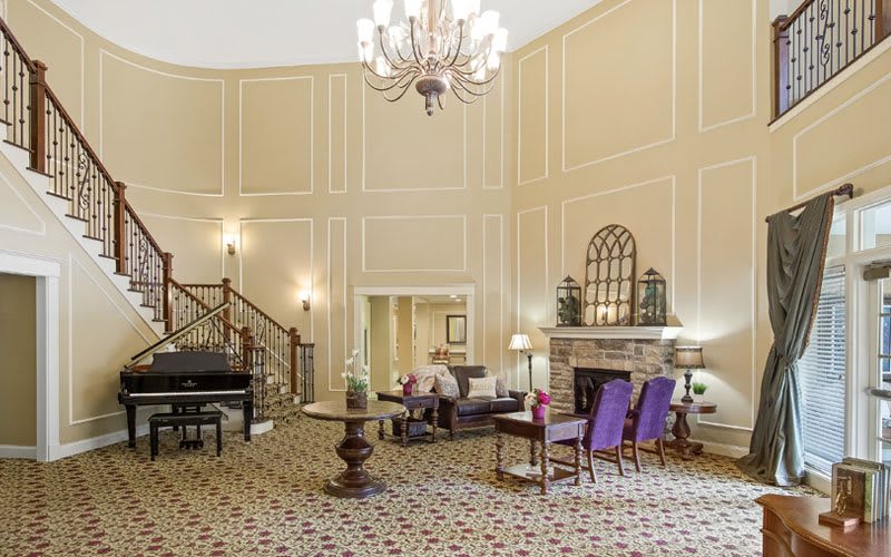 An elegant lobby with a grand chandelier, comfortable seating, and a decorative staircase.