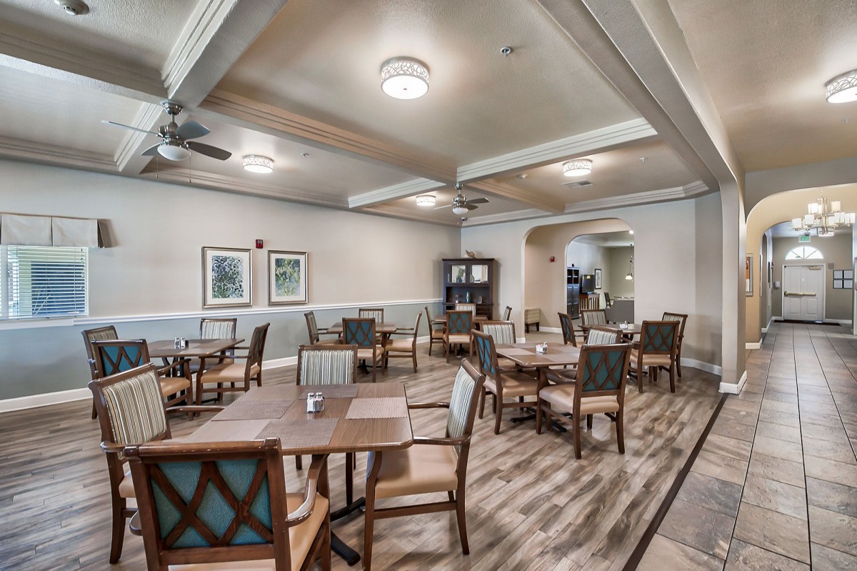 A well-lit dining room with multiple tables and chairs arranged neatly.
