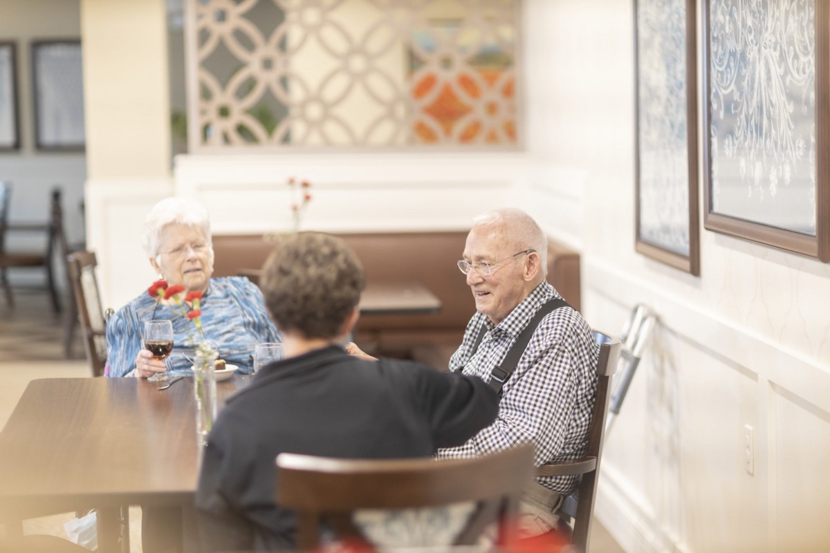 A group of people enjoying a conversation at a dining table indoors.
