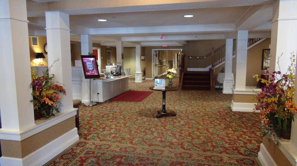 A spacious hotel lobby with a carpeted floor and a reception desk.