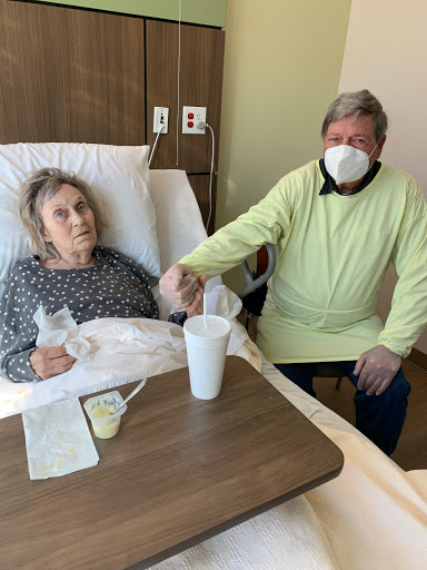 A caregiver provides emotional support to a patient in a hospital room.