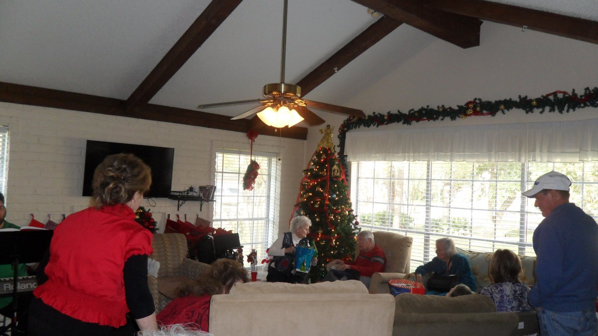 A cozy living room decorated for Christmas with family members gathered around the tree.