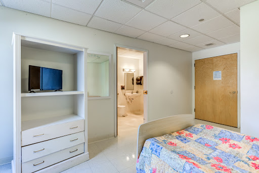 A cozy bedroom with a colorful quilt, featuring a view into an adjoining bathroom.