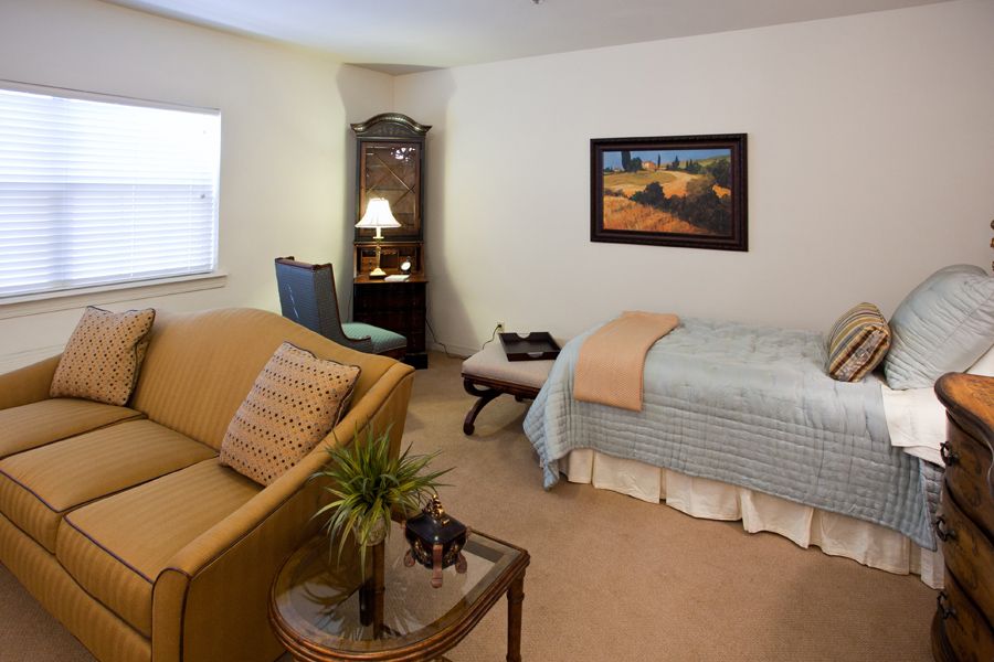 A cozy bedroom with a bed, sofa, desk, and decorative items.