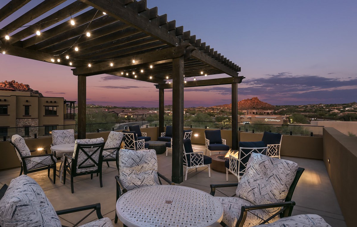 A beautifully lit patio with comfortable seating under a pergola at sunset.