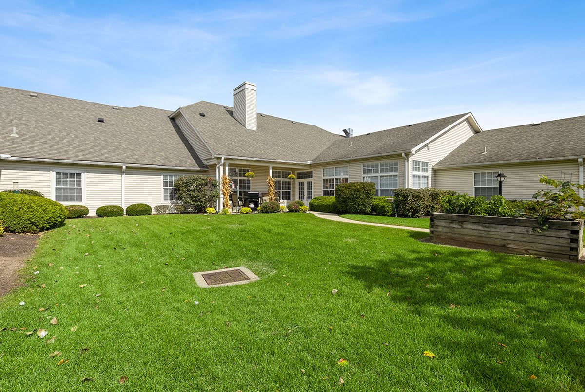 A spacious backyard with a well-maintained lawn and a charming residential house.