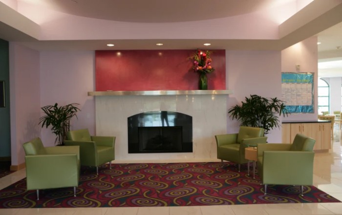 A modern lobby with a fireplace, seating area, and decorative plants.