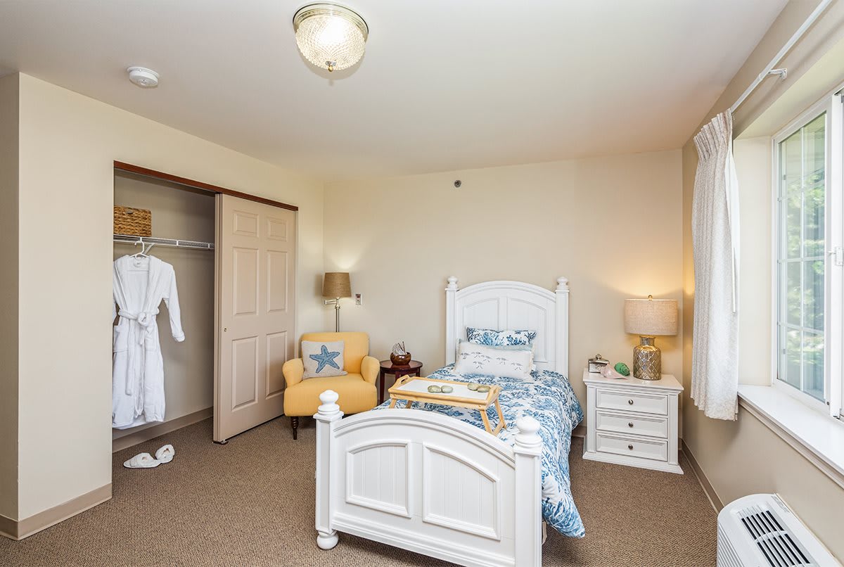 A cozy bedroom with a single bed, armchair, and closet.