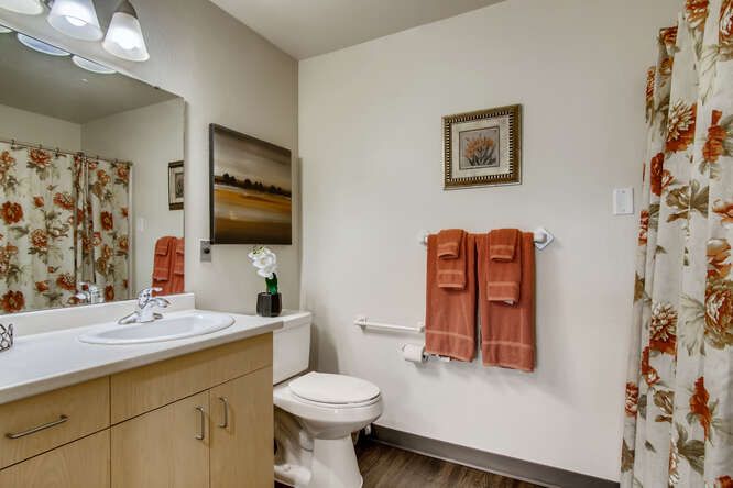 A modern bathroom featuring a sink, toilet, and decorative art on the wall.