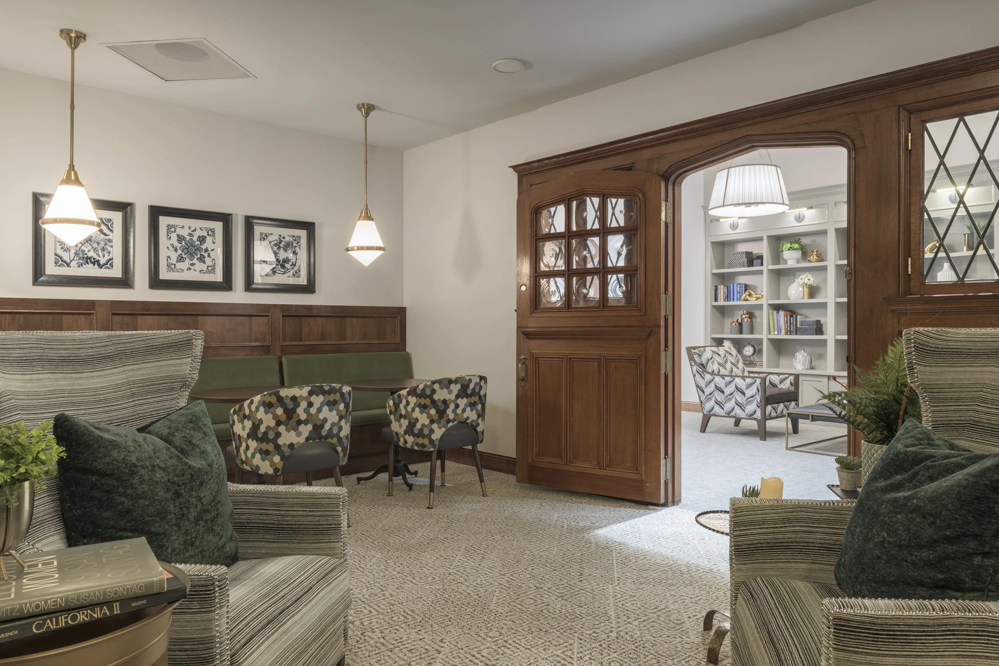 A cozy living room with comfortable seating and a wooden door leading to a room with bookshelves.