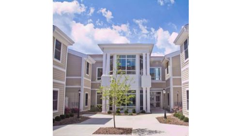 A modern residential building featuring a central courtyard under a bright blue sky.