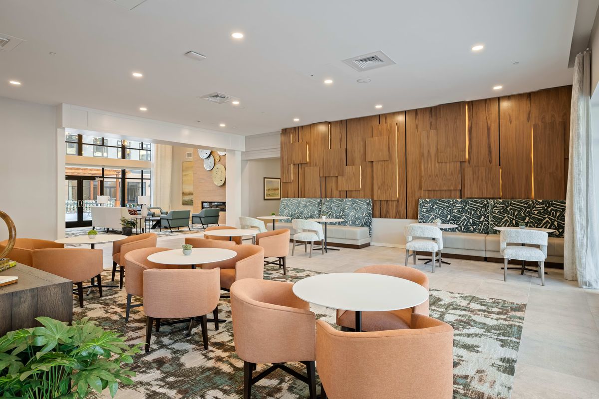 A modern and stylish lounge area featuring a variety of seating options with soft lighting and contemporary wood paneling.