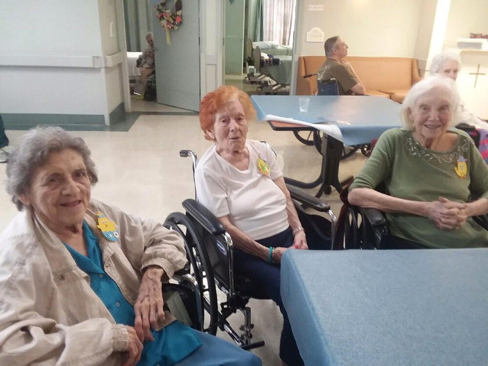 A group of elderly individuals sitting together in a nursing home.
