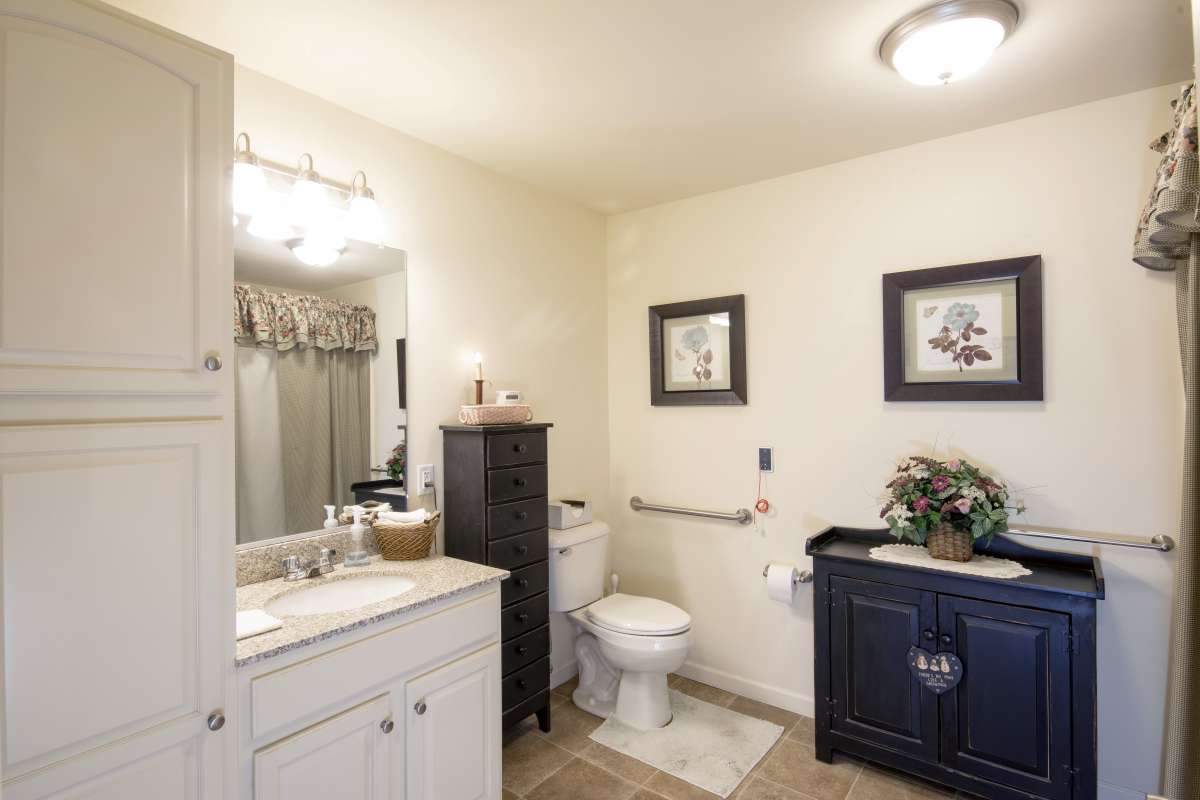 A clean and well-decorated bathroom with a white sink, mirror, and black cabinet.