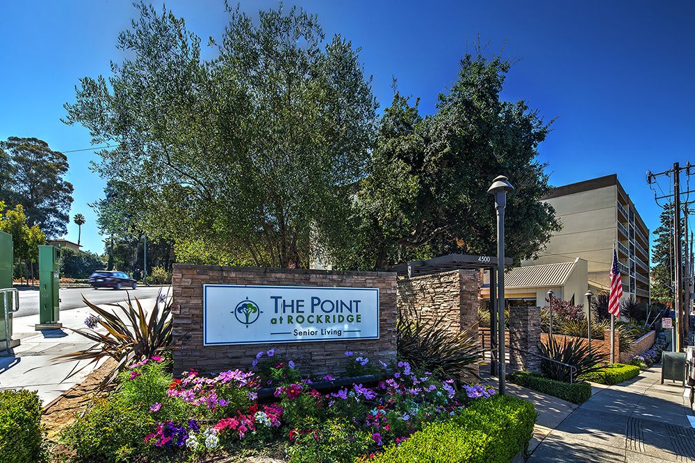 A landscaped entrance with a sign reading 'The Point at Rockridge', surrounded by flowers and trees.