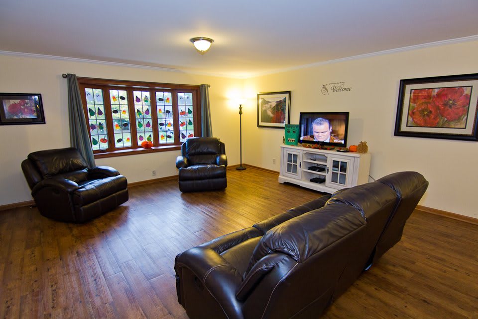 A cozy living room with leather sofas, a television, and large windows.