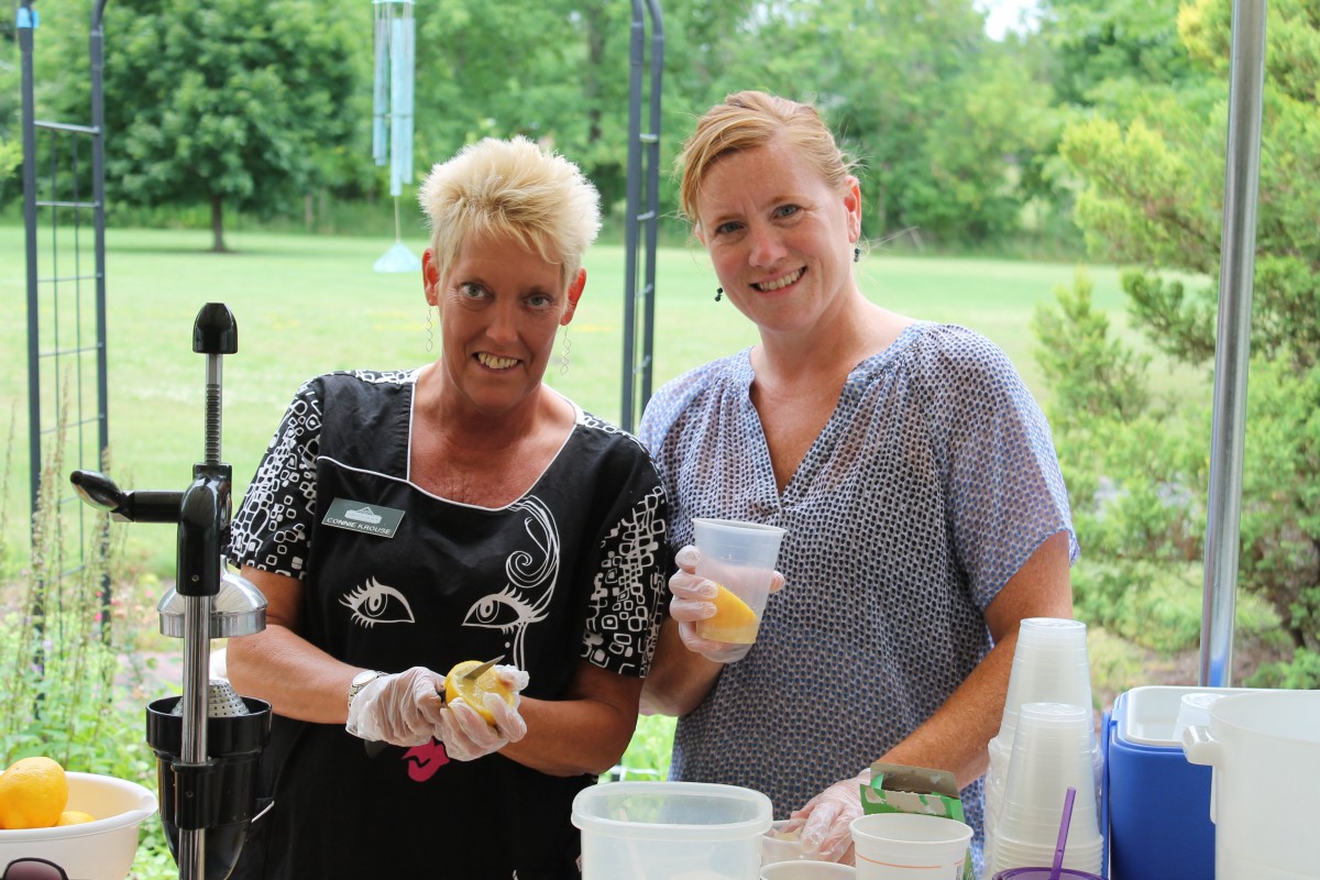Two women preparing food at an outdoor event.