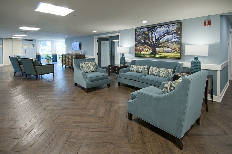 A spacious living room featuring blue furniture and an elegant hardwood floor.