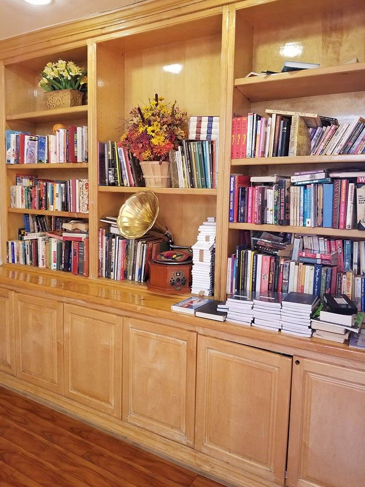 A wooden bookshelf filled with a variety of books, a globe, and decorative items.