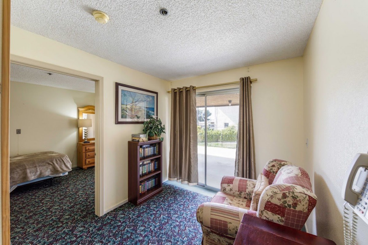 A cozy living room with a sofa, bookshelf, and sliding door leading to the outside.