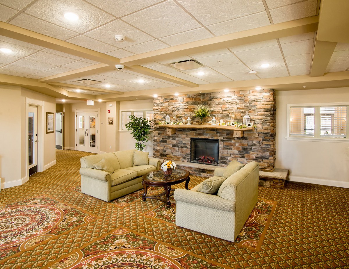 A cozy living room with comfortable sofas and a stone fireplace, featuring warm lighting and elegant decor.