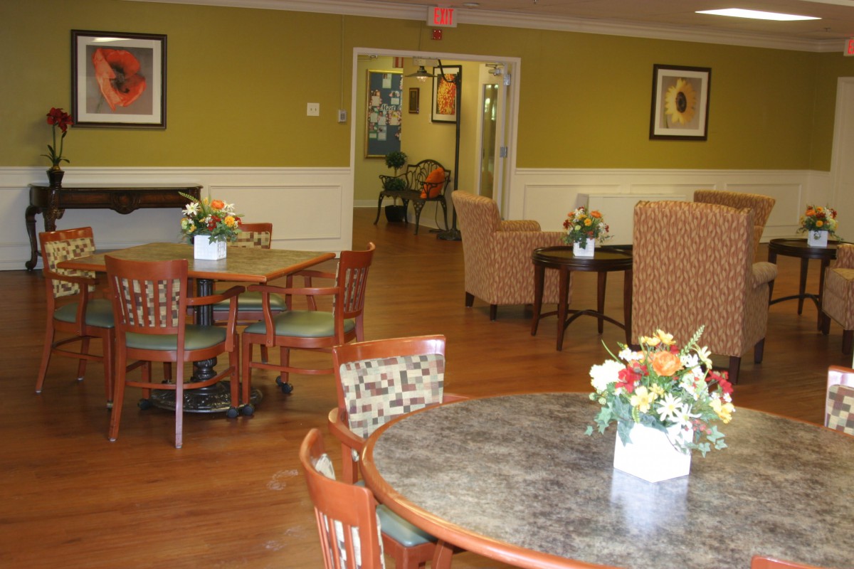 A cozy dining area with tables, chairs, and flower arrangements.