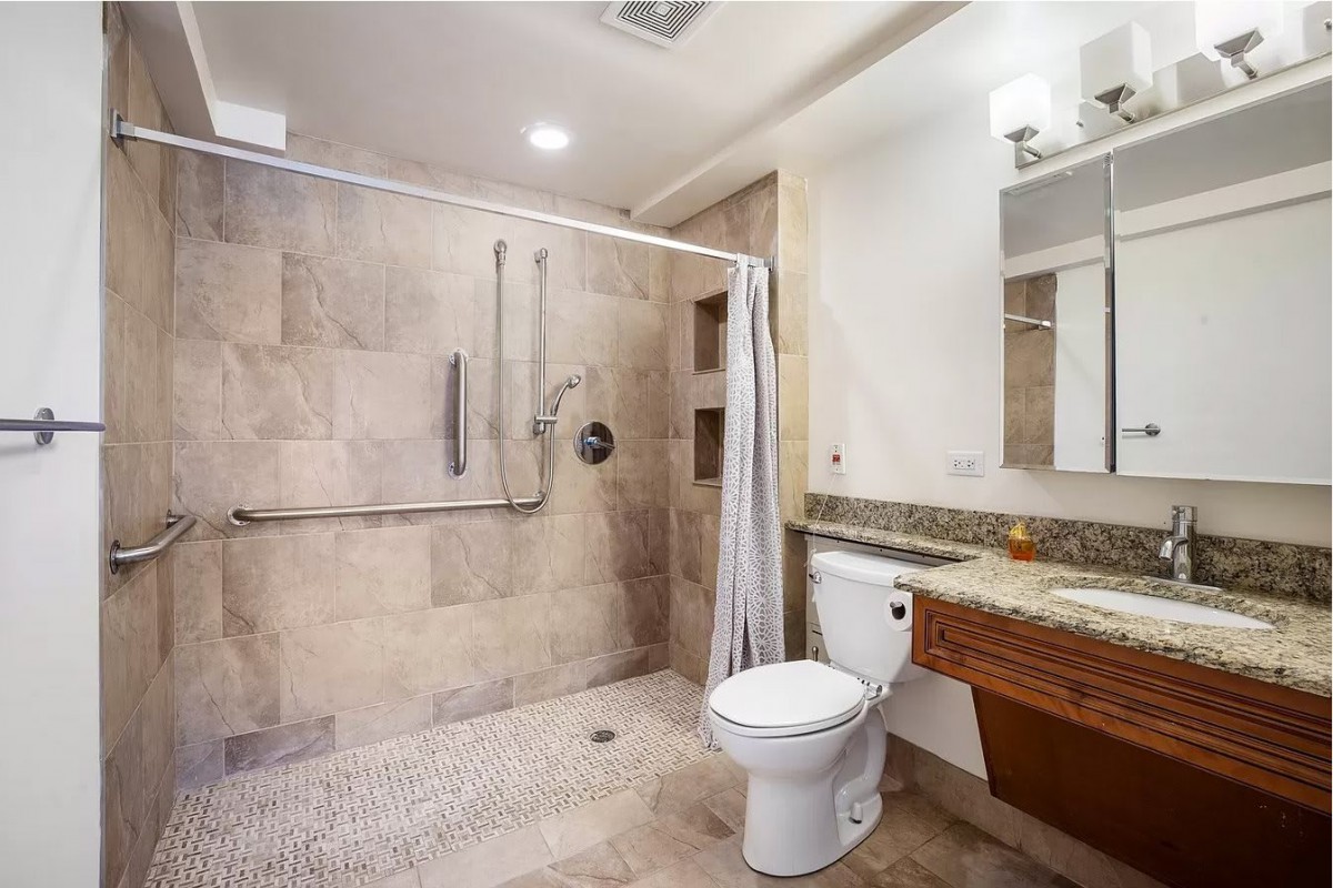A modern and accessible bathroom with a spacious walk-in shower, toilet, and sink.