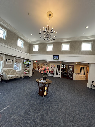 A spacious and elegantly designed lobby featuring a chandelier, seating area, and decorative floral arrangement.