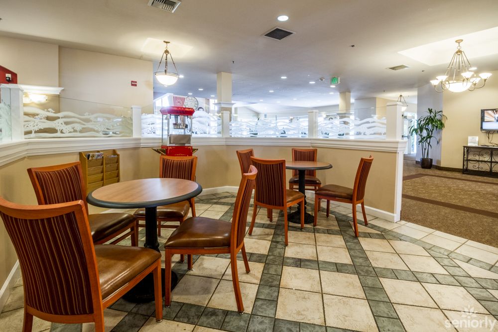 A cozy cafe interior with wooden tables and chairs, featuring a popcorn machine and tiled flooring.