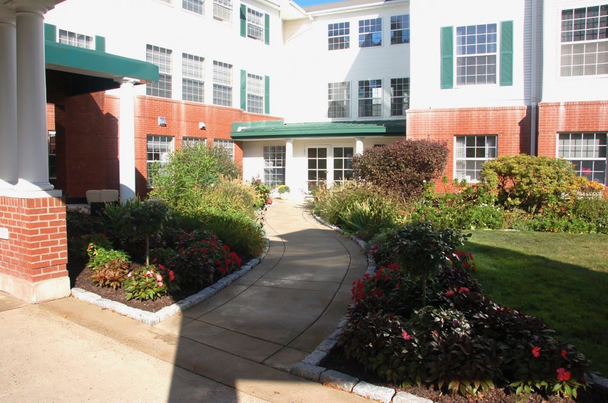 A landscaped garden path leading to a multi-story building with numerous windows.