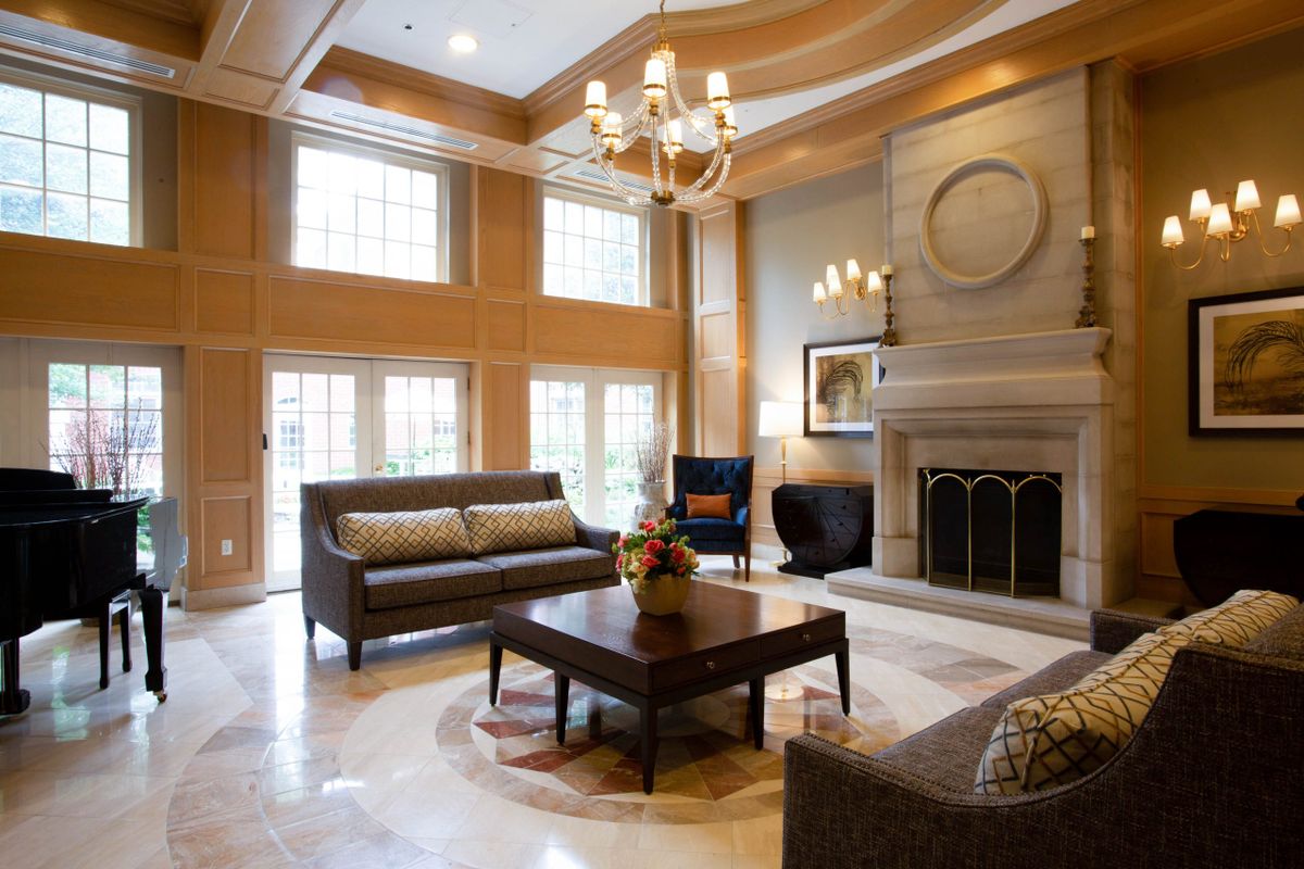 A luxurious living room featuring elegant furniture, a grand chandelier, and large windows for natural light.