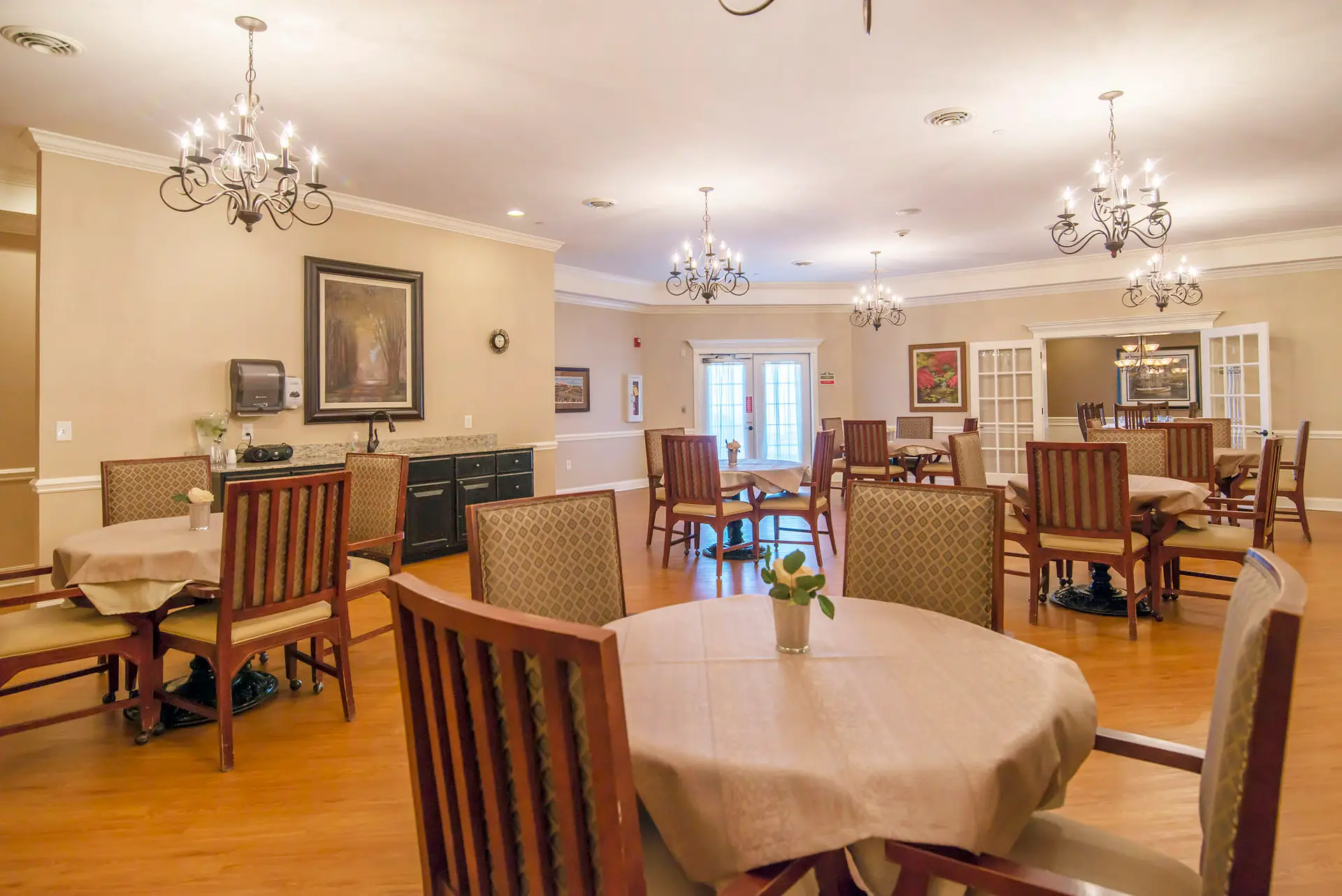 A well-lit dining room with multiple tables and chairs arranged neatly.