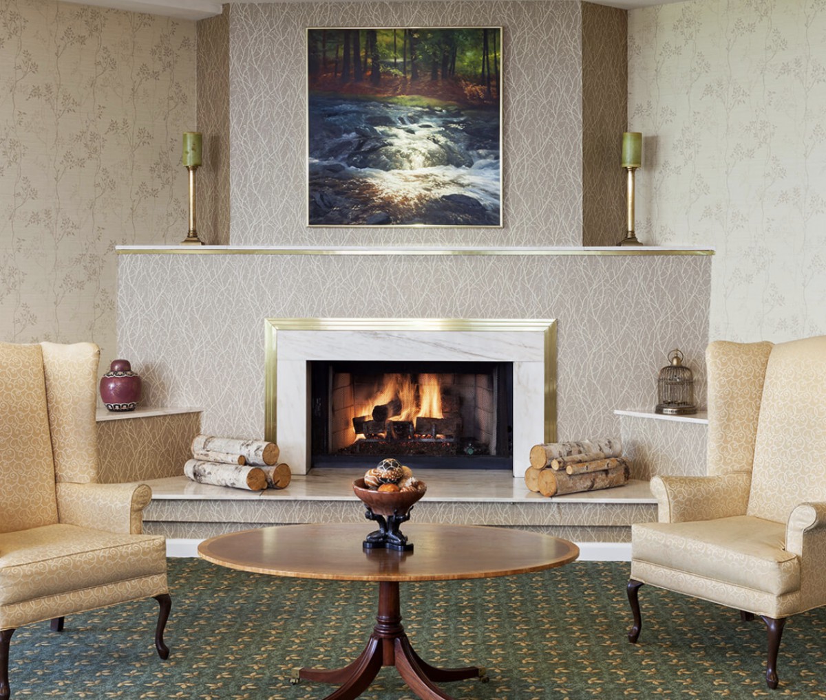 A cozy living room with a fireplace, flanked by two armchairs and a wooden coffee table.