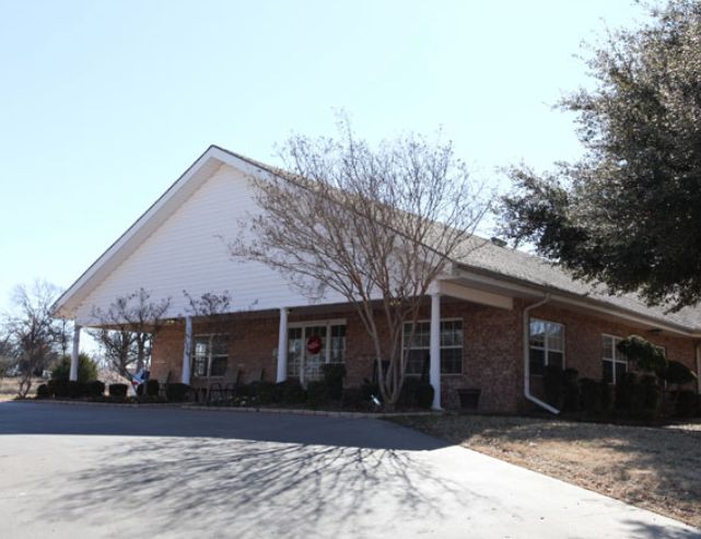 A brick building with a pitched roof surrounded by trees on a clear day.