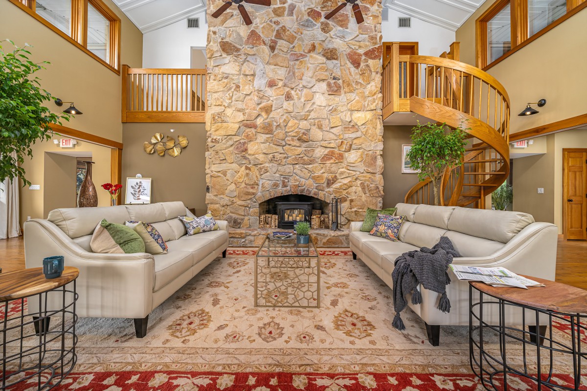 A cozy living room featuring a stone fireplace, elegant sofas, and warm wood accents.