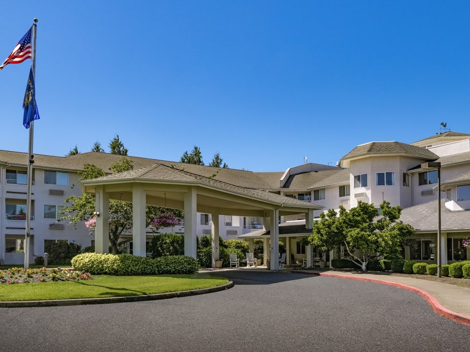 A grand entrance to a large building with a circular driveway and landscaped surroundings.