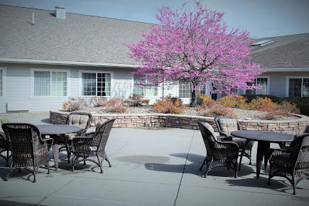 A peaceful outdoor patio with pink-blossoming tree and seating arrangements.