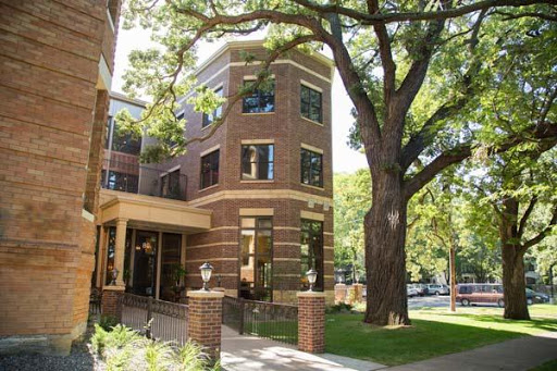 A picturesque brick building surrounded by lush greenery and a large tree.