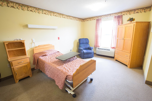 A view of a well-lit hospital room featuring a patient bed, a chair, and ample space for care.