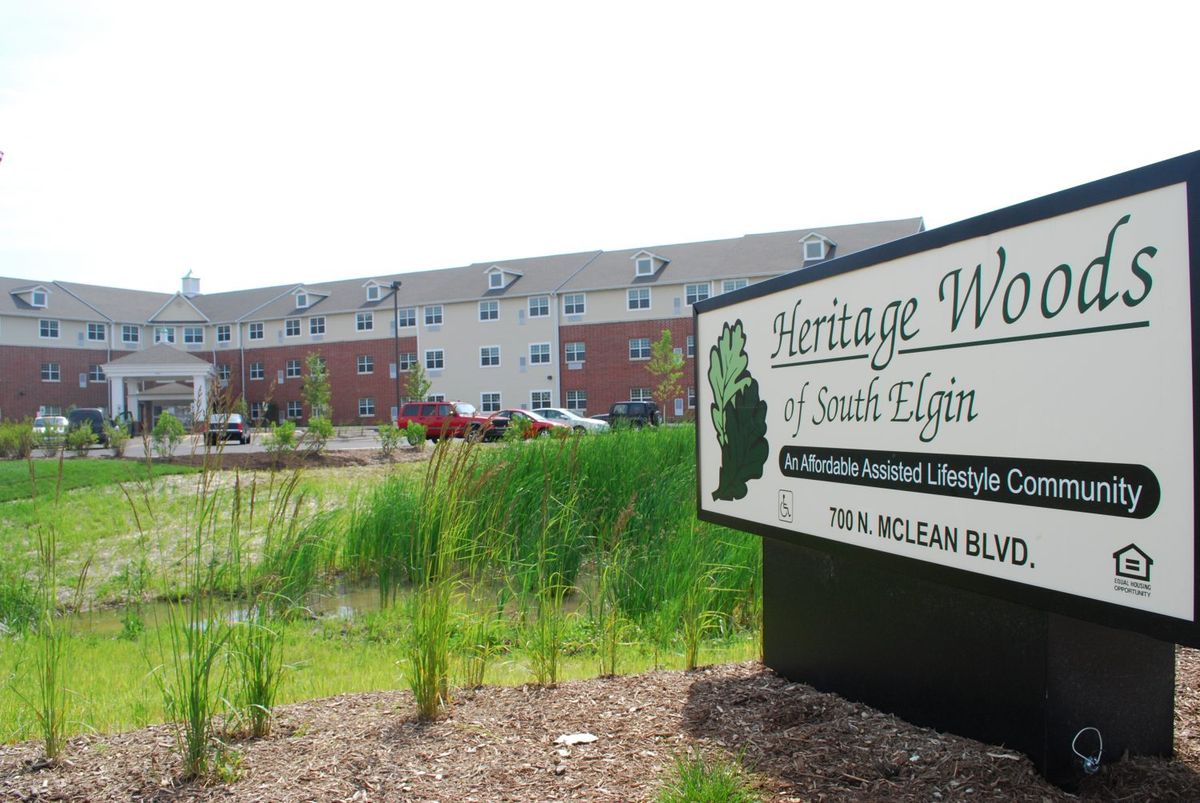A senior living facility with a sign in front and surrounding greenery.