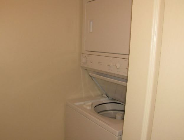 A small laundry area with a stacked washing machine and dryer.