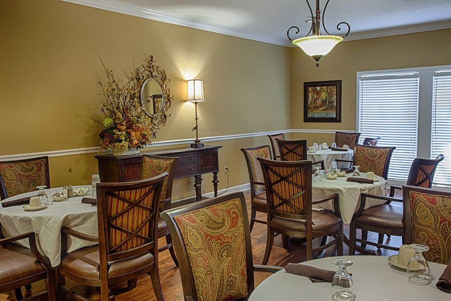 A warmly decorated dining room with elegantly set tables and chairs.
