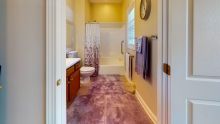 A bright bathroom with a shower, sink, and toilet.