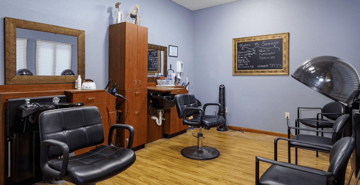 Interior view of a barbershop with chairs and a mirror.