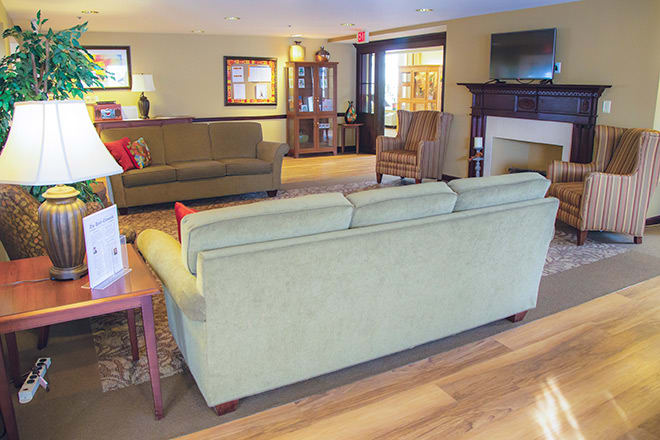 A cozy living room with sofas, a fireplace, and a wooden floor.
