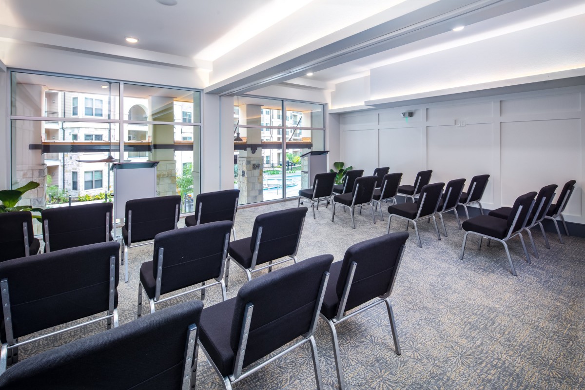 An empty conference room with rows of chairs arranged for a meeting.